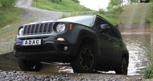 Offroad -Das Offroad-Fahrzeug, ein dunkelgrüner Jeep, verlässt bergauf das Wasserbecken. Parallel zur Wasserdurchfahrt verläuft die steile Bergaufpassage.
